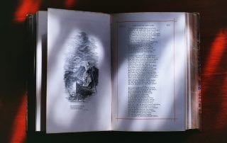 Antique poetry book open to 'The Lady of the Lake' with a black & white image on the other page, resting on a red background